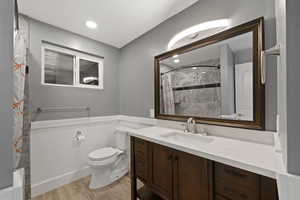 Bathroom featuring wood-type flooring, a shower with curtain, vanity, and toilet