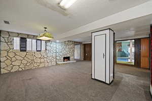 Basement featuring dark carpet, a textured ceiling, and a fireplace