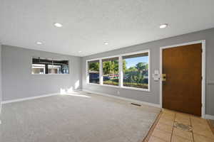 Foyer featuring a textured ceiling and light colored carpet