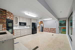 Kitchen featuring brick wall, a textured ceiling, and black appliances