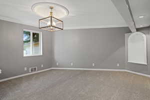 Spare room featuring carpet floors, ornamental molding, and a chandelier