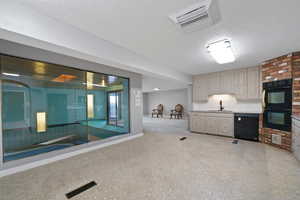 Interior space featuring light carpet, a textured ceiling, sink, and black appliances