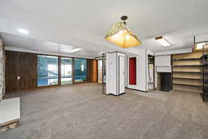 Interior space featuring a textured ceiling, gas water heater, wood walls, and carpet floors