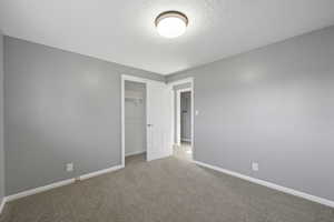 Unfurnished bedroom with a textured ceiling, a closet, and carpet flooring