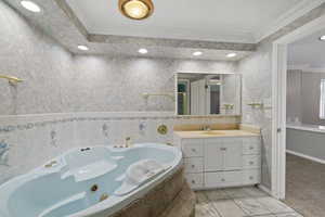 Bathroom with a bath, ornamental molding, and vanity