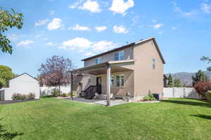 Rear view of house with a patio, a mountain view, ceiling fan, and a yard