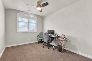 Carpeted home office with lofted ceiling and ceiling fan