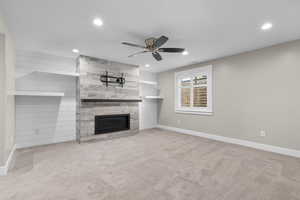 Unfurnished living room featuring ceiling fan, light colored carpet, and a fireplace