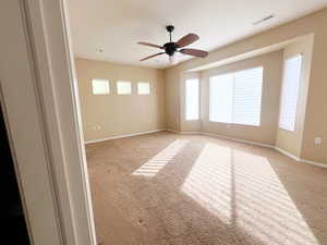 Carpeted spare room featuring ceiling fan