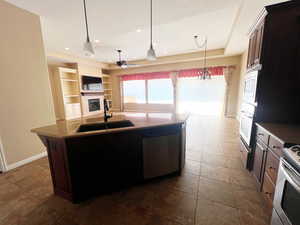 Kitchen with sink, a brick fireplace, stainless steel appliances, a center island, and ceiling fan with notable chandelier