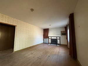 Unfurnished living room featuring wood-type flooring, radiator, and a textured ceiling