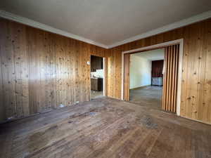 Empty room featuring radiator, hardwood / wood-style flooring, wooden walls, and crown molding