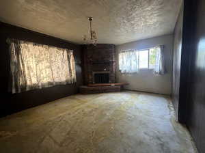 Unfurnished living room with an inviting chandelier and a brick fireplace