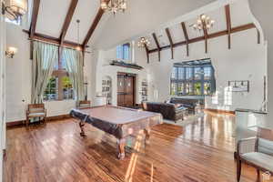 Playroom featuring beam ceiling, high vaulted ceiling, a notable chandelier, billiards, and hardwood / wood-style floors