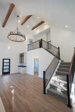 Unfurnished living room featuring beamed ceiling, wood-type flooring, and high vaulted ceiling