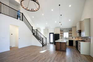 Kitchen with a kitchen island, a towering ceiling, pendant lighting, and black appliances