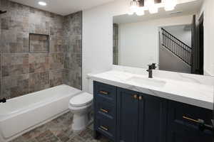 Full bathroom featuring tiled shower / bath, vanity, and toilet