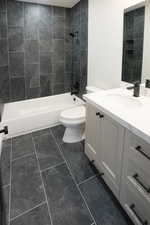 Full bathroom with tiled shower / bath combo, vanity, and toilet