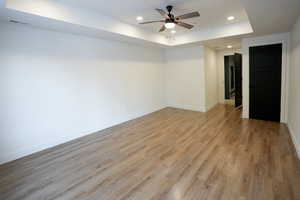 Spare room with light hardwood / wood-style flooring, a raised ceiling, and ceiling fan