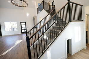 Staircase with a high ceiling, wood-type flooring, and a chandelier