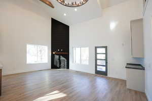 Unfurnished living room with a fireplace, high vaulted ceiling, and light hardwood / wood-style floors