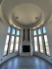 Unfurnished living room with a stone fireplace, a tray ceiling, a towering ceiling, and dark hardwood / wood-style flooring