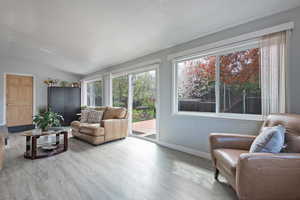 Living room with vaulted ceiling, a textured ceiling, and hardwood / wood-style flooring