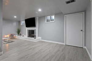 Unfurnished living room featuring light wood-type flooring, a textured ceiling, and a fireplace