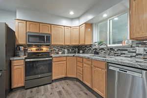 Kitchen featuring sink, light hardwood / wood-style flooring, backsplash, appliances with stainless steel finishes, and light brown cabinetry