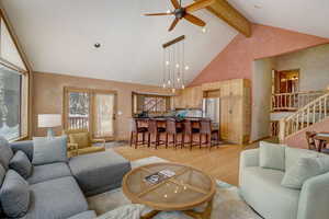 Living room with light hardwood / wood-style flooring, beam ceiling, ceiling fan, and high vaulted ceiling