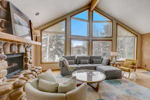 Living room with a fireplace, lofted ceiling with beams, and light hardwood / wood-style flooring