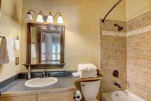 Full bathroom with tiled shower / bath combo, vanity, and toilet