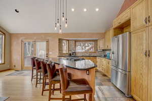 Kitchen with appliances with stainless steel finishes, a kitchen bar, a kitchen island, and light brown cabinetry