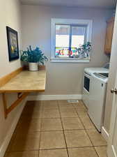 Laundry room with washer and clothes dryer, cabinets, and light tile patterned floors