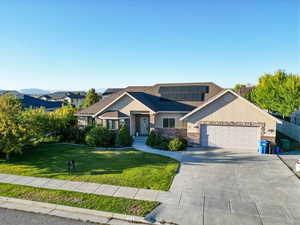 View of front of house with a garage, solar panels, and a front lawn