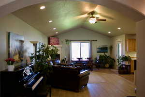 Living room featuring a textured ceiling, lofted ceiling, ceiling fan, and light hardwood / wood-style flooring