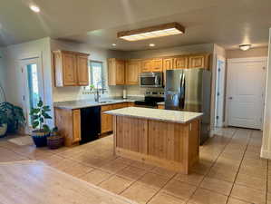 Kitchen with sink, a center island, stainless steel appliances, and light tile patterned floors