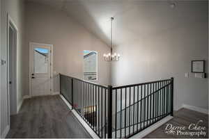 Hall featuring high vaulted ceiling, a chandelier, a textured ceiling, and dark hardwood / wood-style flooring