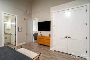 Bedroom with ensuite bathroom, a closet, and light hardwood / wood-style floors