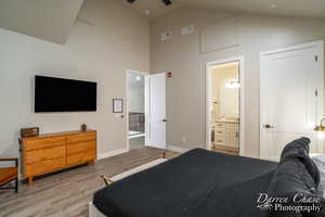 Bedroom featuring high vaulted ceiling, connected bathroom, and light hardwood / wood-style floors