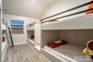 Bedroom with lofted ceiling and light wood-type flooring