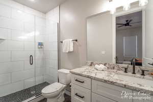 Bathroom with ceiling fan, walk in shower, vanity, and toilet