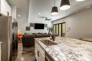 Kitchen with pendant lighting, sink, white cabinets, stainless steel refrigerator with ice dispenser, and ceiling fan