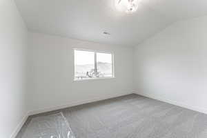 Carpeted spare room with a mountain view and vaulted ceiling