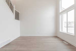 Unfurnished room featuring light hardwood / wood-style flooring and a high ceiling