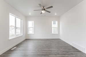 Empty room with ceiling fan and dark hardwood / wood-style flooring