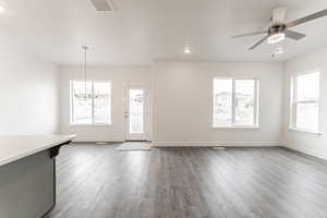 Unfurnished living room featuring dark hardwood / wood-style flooring and ceiling fan with notable chandelier