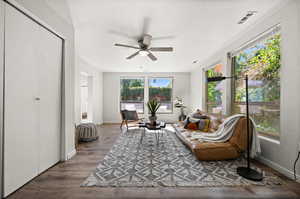 Living room featuring ceiling fan, dark wood-type flooring, and a wealth of natural light