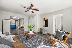 Living room with ceiling fan and dark hardwood / wood-style floors