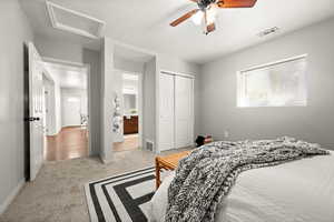 Carpeted bedroom with ceiling fan and a closet